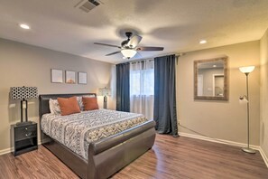 A bedroom with a bed, nightstands, a ceiling fan, a large mirror, and a floor lamp. - Lake Access & Pool: Spacious Freeport Home! (Freeport)