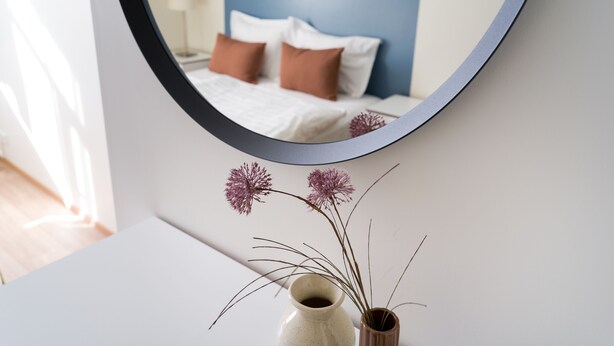 A bedroom with a bed, pillows, and a bedside table with a vase of dried flowers. - Salt Guesthouse (Siglufjörður)