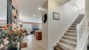 A spacious living area with a staircase, a dining area, and a kitchen in the background. - 4BR Disney Home w/ Private Pool • Sleeps 11 (Kissimmee)