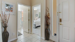 A hallway with white doors, a framed picture on the wall, and two vases with dried plants. - 4BR Disney Home w/ Private Pool • Sleeps 11 (Kissimmee)