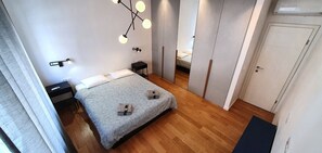Un dormitorio moderno con cama, mesitas de noche, lámpara colgante y armario.