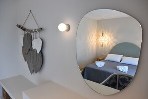 Ein Schlafzimmer mit einem Bett, einem Wandspiegel und einer Wanddekoration.