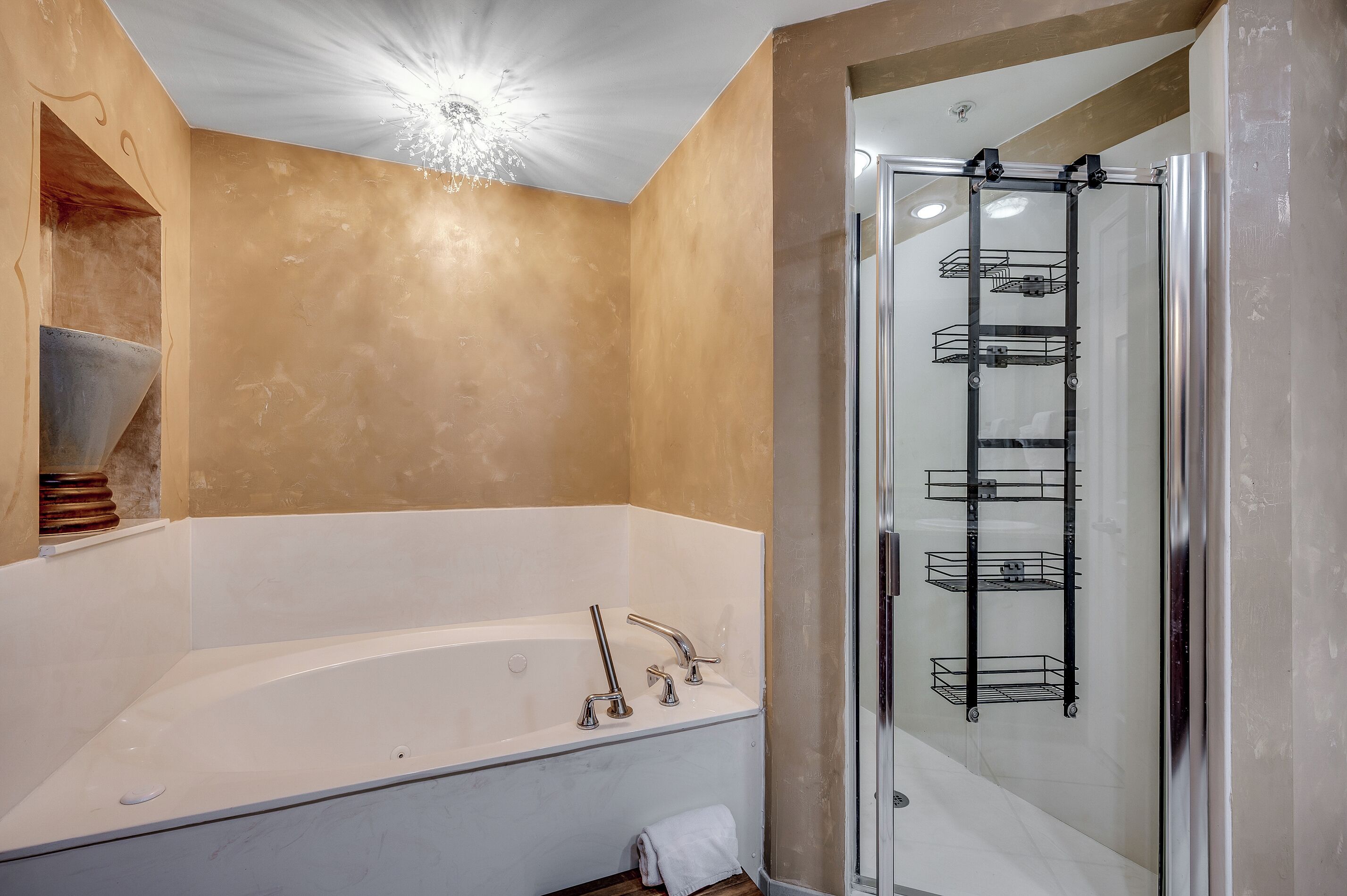 A modern bathroom with a freestanding bathtub, a glass-enclosed shower, and a metal shelf unit.