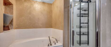 A modern bathroom with a freestanding bathtub, a glass-enclosed shower, and a metal shelf unit.