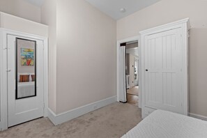 Quarto com porta, cama e corredor que dá para outro cômodo.