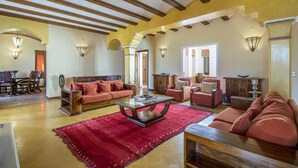 A spacious living room with a red rug, wooden furniture, and a staircase leading to another level. - Quinta Dionysus | 6 Bedrooms | Own Vineyard | Albufeira (Albufeira)