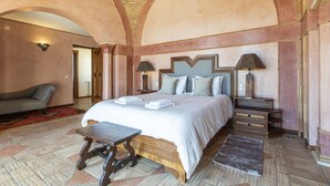 A spacious bedroom with a large bed, two bedside tables with lamps, a wooden bench, and a patterned rug. - Quinta Dionysus | 6 Bedrooms | Own Vineyard | Albufeira (Albufeira)