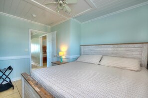 Ein Schlafzimmer mit einem Bett, einem Nachttisch, einer Lampe und einem Deckenventilator.