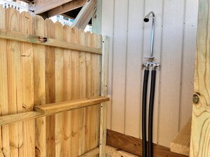 A wooden fence with a metal showerhead attached to a wall.