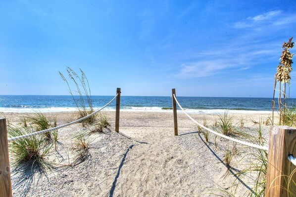 Une plage de sable bordée d’une barrière faite de cordes qui mène à l’océan.