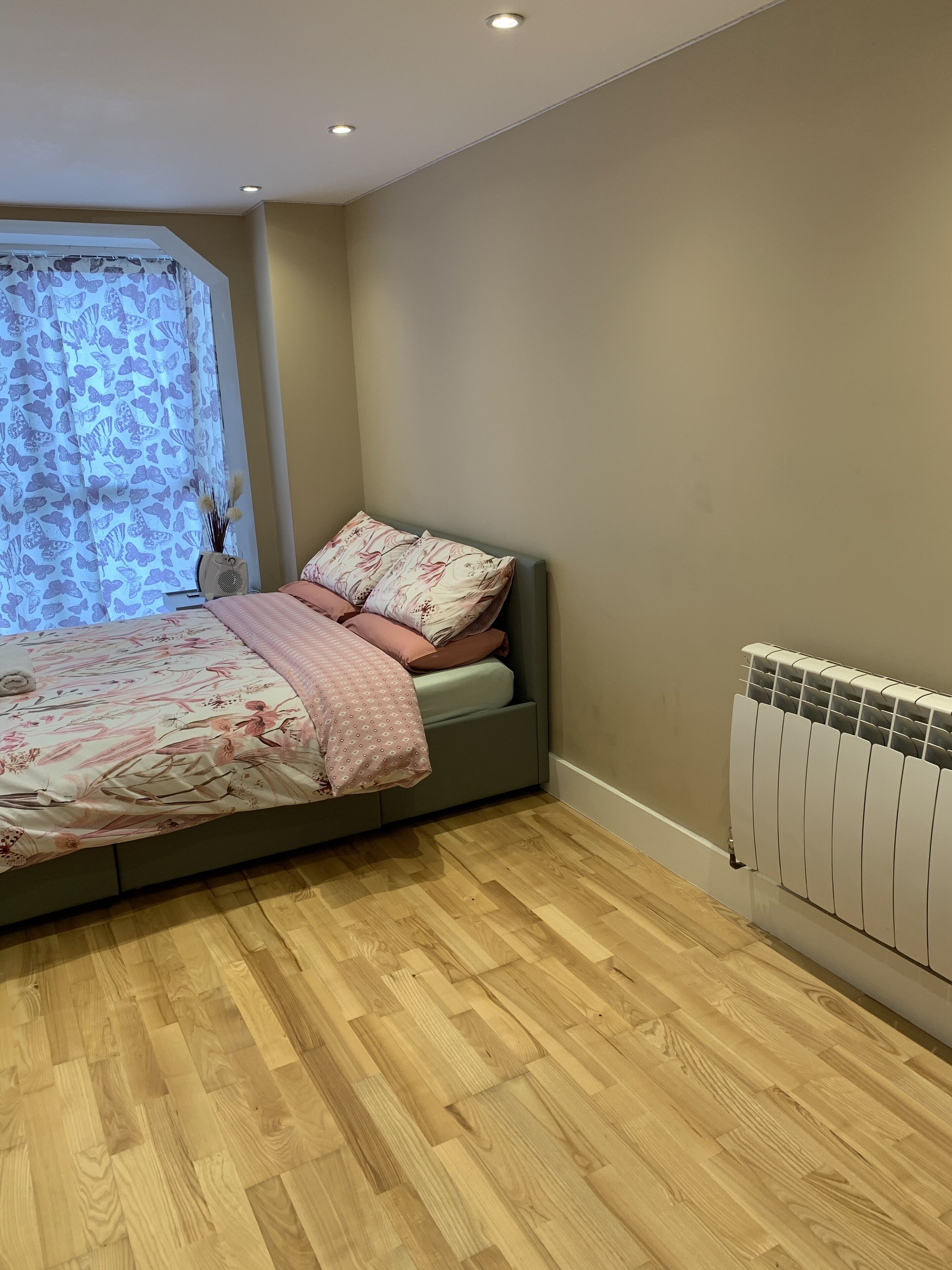 Camera da letto con un letto, un termosifone e una finestra con tende a motivi.
