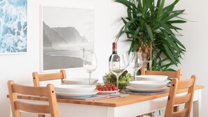 Een eettafel met witte borden, een wijnfles en glazen, omringd door houten stoelen.