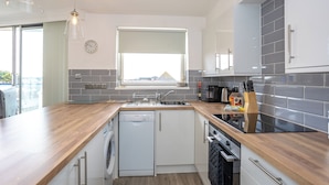 Een moderne keuken met een vaatwasser, spoelbak en een raam met uitzicht op een stadsbeeld.