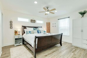 A bedroom with a wooden bed, a ceiling fan, a white wardrobe, and a window with curtains. - Sea Forever - Front Row, Fire Pit & Miles of Surf! (Surfside Beach)