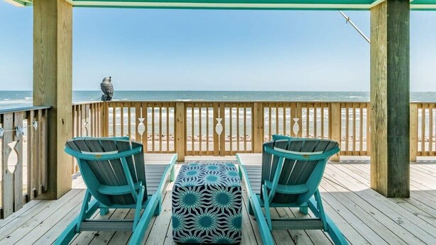 A wooden deck with two chairs and a patterned ottoman, overlooking a beach. - Sea Forever - Front Row, Fire Pit & Miles of Surf! (Surfside Beach)