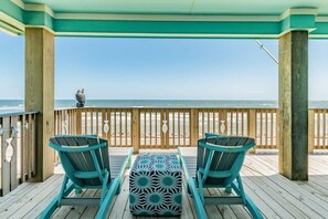 A wooden deck with two chairs and a patterned ottoman, overlooking a beach. - Sea Forever - Front Row, Fire Pit & Miles of Surf! (Surfside Beach)