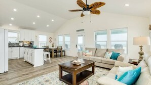 A spacious living area with a ceiling fan, a dining table with chairs, a sofa, and a coffee table. - Sea Forever - Front Row, Fire Pit & Miles of Surf! (Surfside Beach)