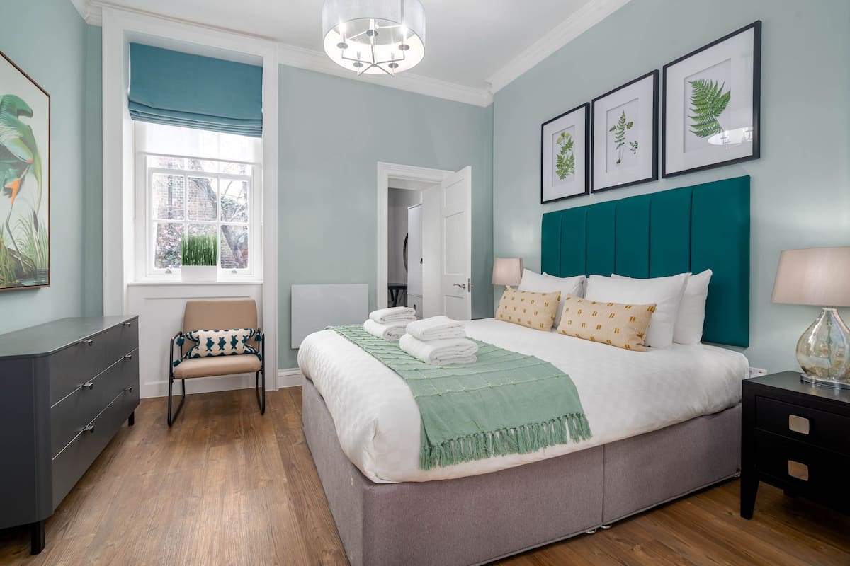 A bedroom with a large bed, a chair, a dresser, and a nightstand.
