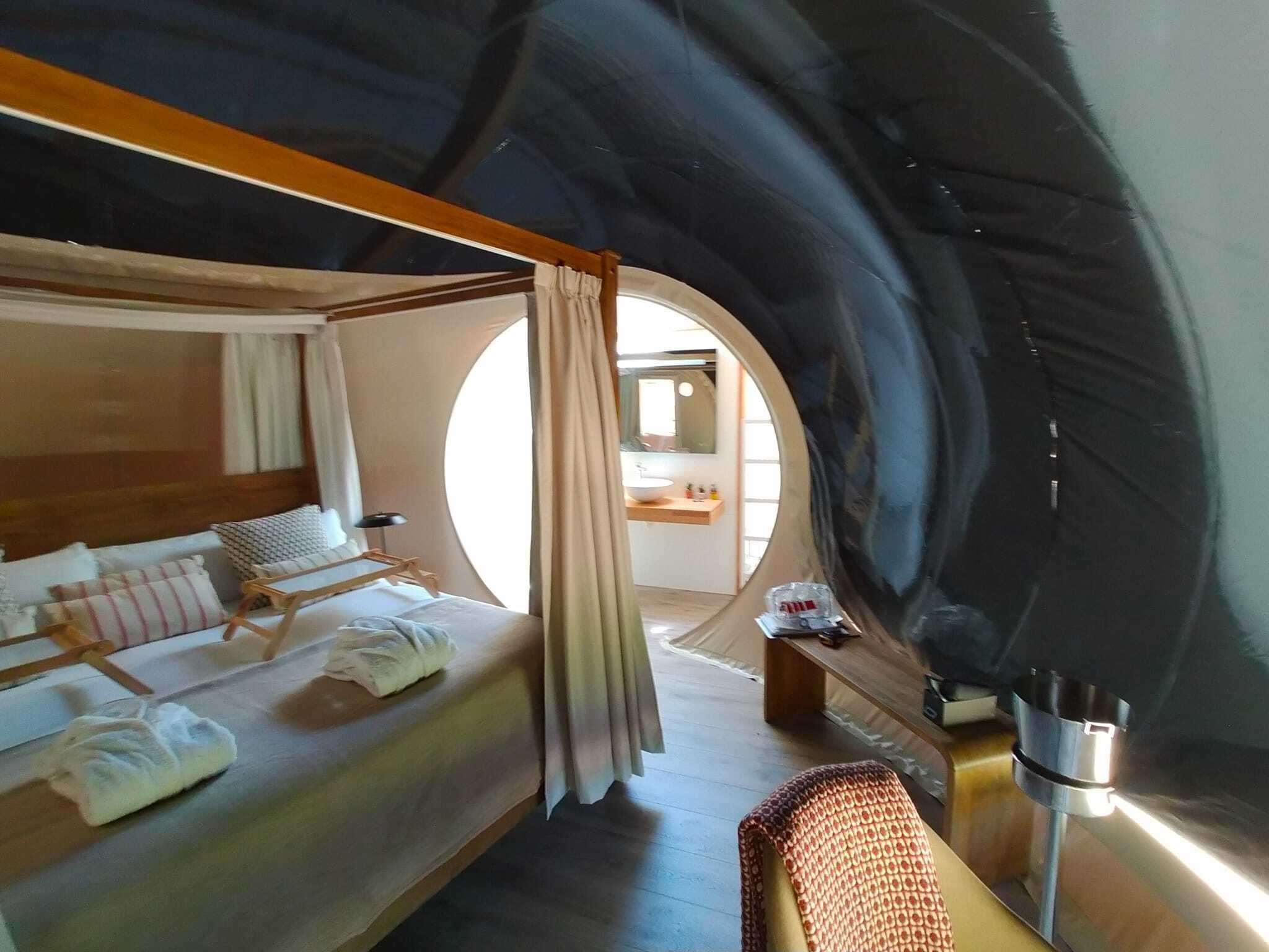 Una habitación acogedora y circular con una cama, una mesita y un espejo.