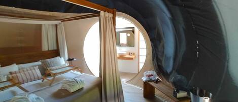 Una habitación acogedora y circular con una cama, una mesita y un espejo.