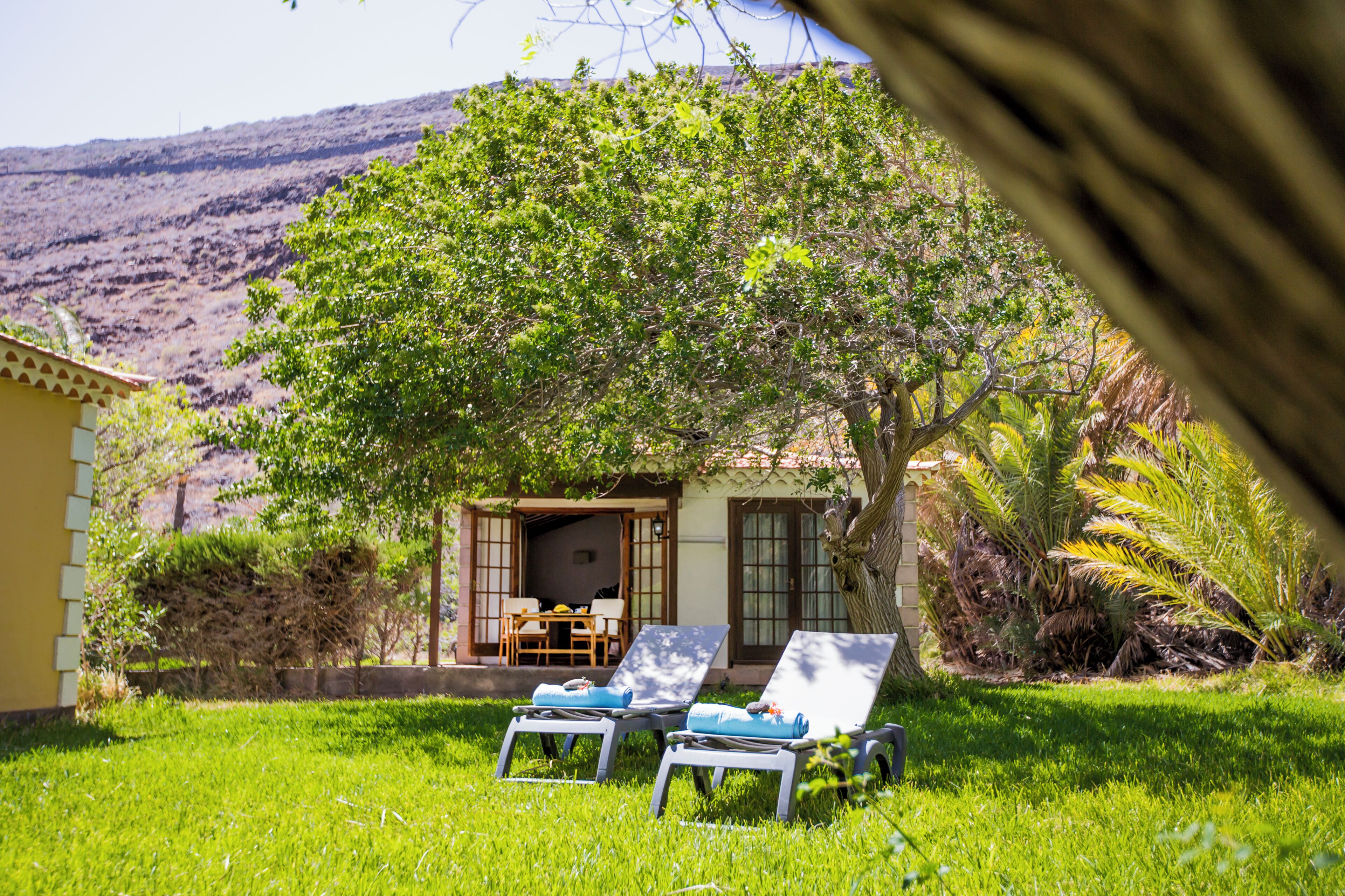 A house with a patio, two lounge chairs, and a table.