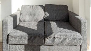Un sofá gris en una habitación con un cuadro en la pared.