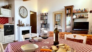 A cozy living room with a checkered tablecloth, a fireplace, a bookshelf, and a television. - Casa Sophia, pool with sea view - garden, barbecue and parking are pri (Guardistallo)