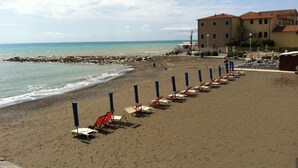 A beach with rows of sun loungers and a building in the background. - Casa Sophia, pool with sea view - garden, barbecue and parking are pri (Guardistallo)