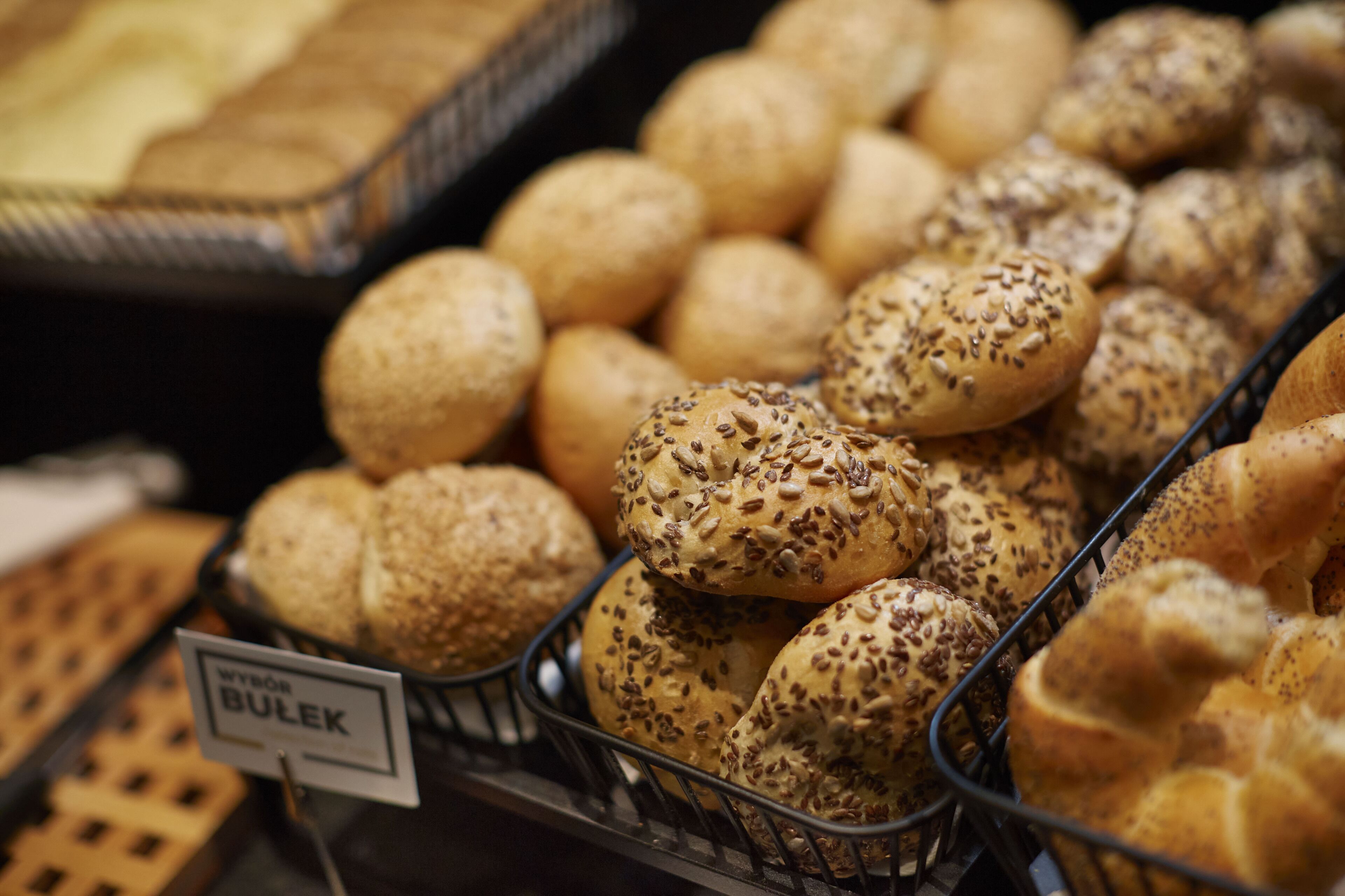 A display of various baked goods, including bread rolls and buns, in a bakery setting.