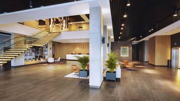 A spacious lobby with a staircase, seating areas, and a reception desk.
