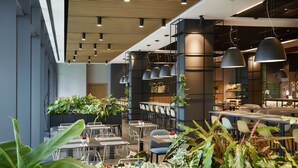 A modern restaurant with high ceilings, pendant lighting, and a variety of seating arrangements. - Q Hotel Plus Wrocław Bielany (Kobierzyce)