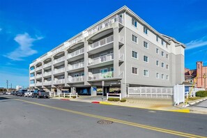 Un hôtel à plusieurs étages doté de balcons, d’un parking et surplombant un ciel d’un bleu limpide.
