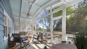 A covered outdoor deck with wooden furniture, including chairs and a table, and a ceiling fan. - Fincastle - 5 bedroom, Oceanfront (Pawleys Island)