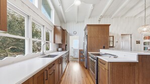 A kitchen with wooden cabinets, a white countertop, and a view of the outdoors. - Fincastle - 5 bedroom, Oceanfront (Pawleys Island)