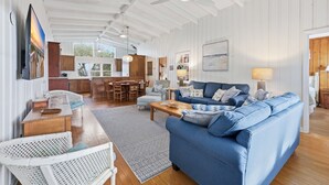 A spacious living area with a blue sofa, wooden coffee table, and a dining table with chairs. - Fincastle - 5 bedroom, Oceanfront (Pawleys Island)