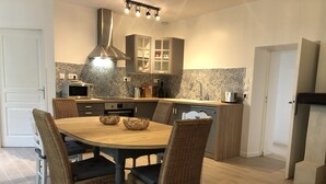 Une cuisine moderne avec une table à manger ronde, des chaises en osier et des placards intégrés.
