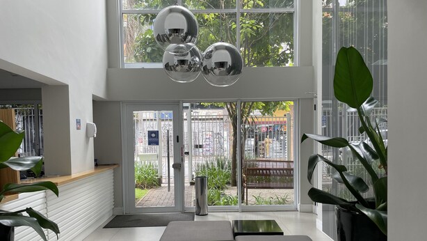 A modern lobby with a reception desk, seating area, and large windows offering views of the outside.