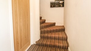 A wooden door, carpeted stairs, and a wall-mounted light fixture. - 16 Norfolk Heights (King's Lynn)