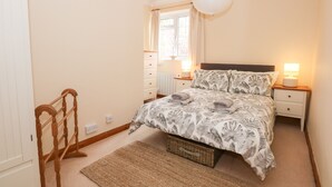 A bedroom with a bed, bedside lamps, a window, and a wooden chair. - 16 Norfolk Heights (King's Lynn)