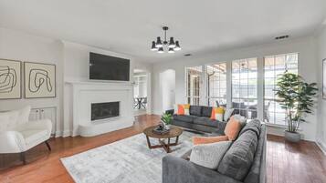 Un salon spacieux avec une cheminée, un grand canapé gris, un fauteuil blanc et une table basse.