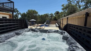 A hot tub area with a pool and picnic tables, surrounded by a wooden fence and a metal railing. - Spacious Home for 12 Near Ark - w/Pool & Hot Tub! (Williamstown)