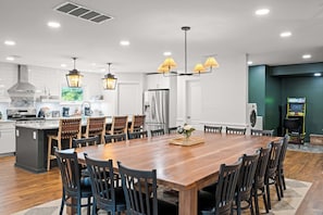 A spacious kitchen with a large wooden dining table, modern appliances, and pendant lighting.