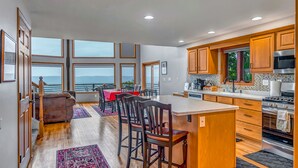 A spacious kitchen with a large island, wooden cabinets, and a view of the ocean.
