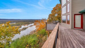 A wooden deck with a view of a river and autumn foliage.