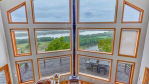 A room with large windows offering views of a lake and greenery.