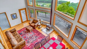 A spacious living room with large windows, a fireplace, and a view of a lake.
