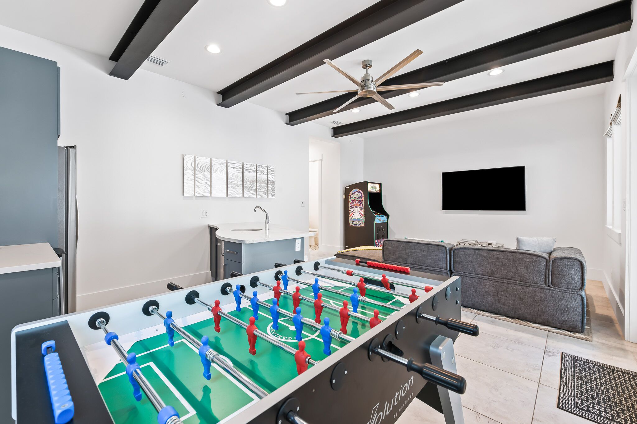 A modern living room with a foosball table, a sofa, and a flat-screen TV.