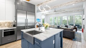 A modern kitchen with a large island, built-in appliances, and a view to a living area with a sofa and a dining table. - Gulf Views, LSV, Pool and 2 Blocks to Beach (Santa Rosa Beach)