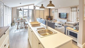 A modern kitchen with a central island, built-in oven, and a dining area with a table and chairs.