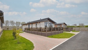A modern single-story house with a covered patio, a paved driveway, and a well-maintained lawn.